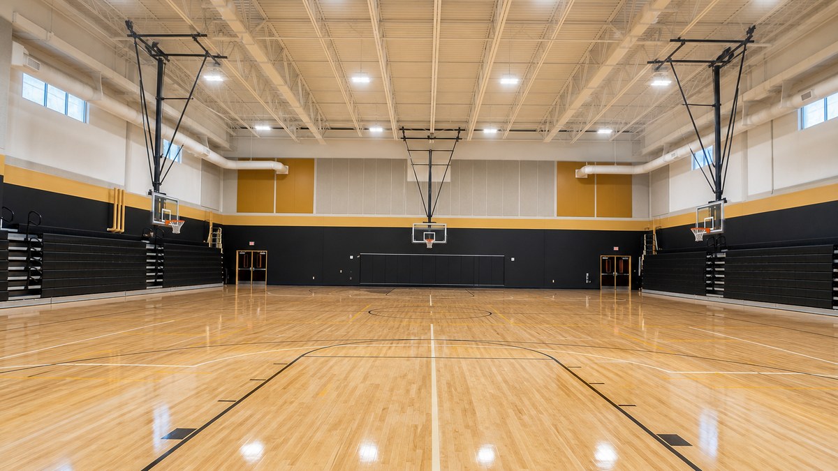 Indoor school gymnasium with bright, even LED high bay sports lighting over a basketball court
